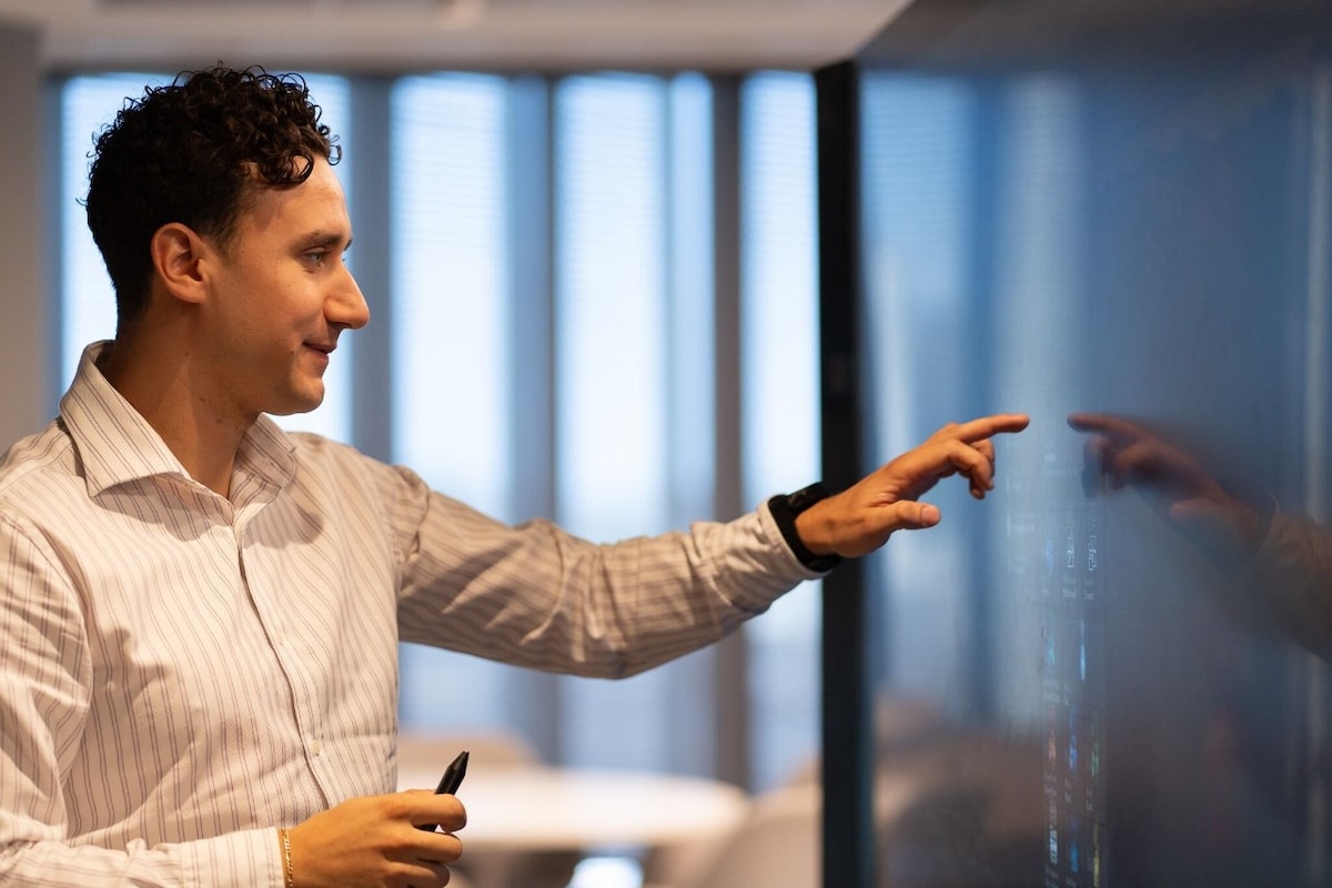 Three men high vis walking along a grass path through a solar panel farm