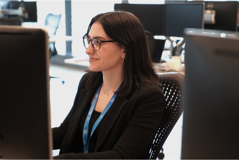 Woman working pictured between two monitors.