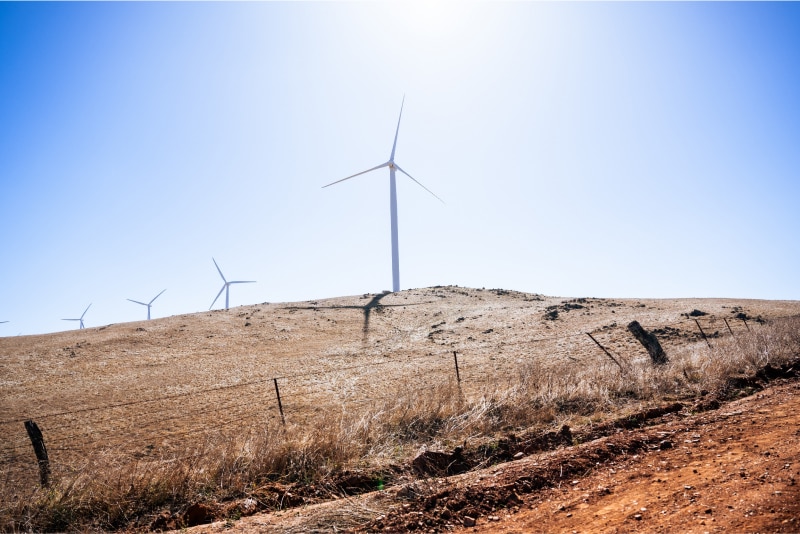 Scenic photo of a wind turbine with the sun shining through it