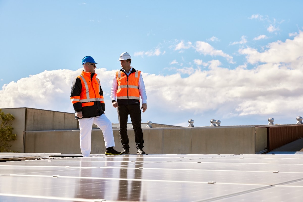 Two people standing on top of the Bega rooftop solar project