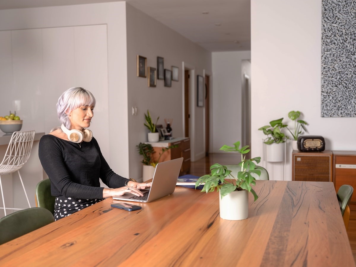 Woman sitting at a table using her laptop in the kitchen.