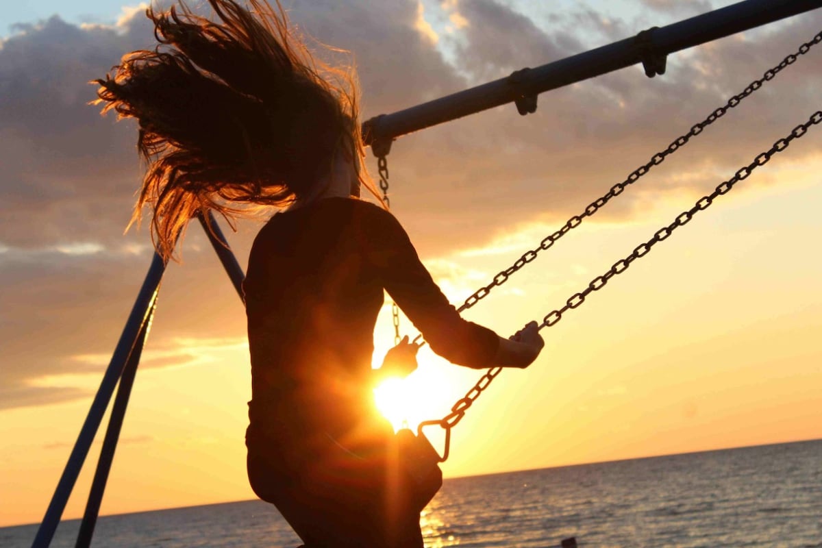 A woman on a swing at sunset near the ocean