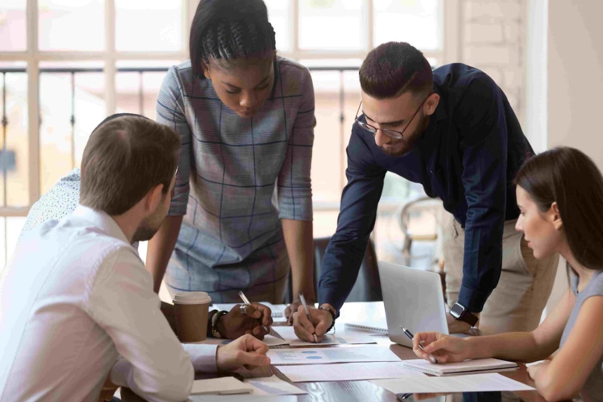 Four work colleagues confer notes at a table