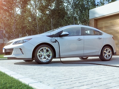 Honda EV being charged in the driveway of a home