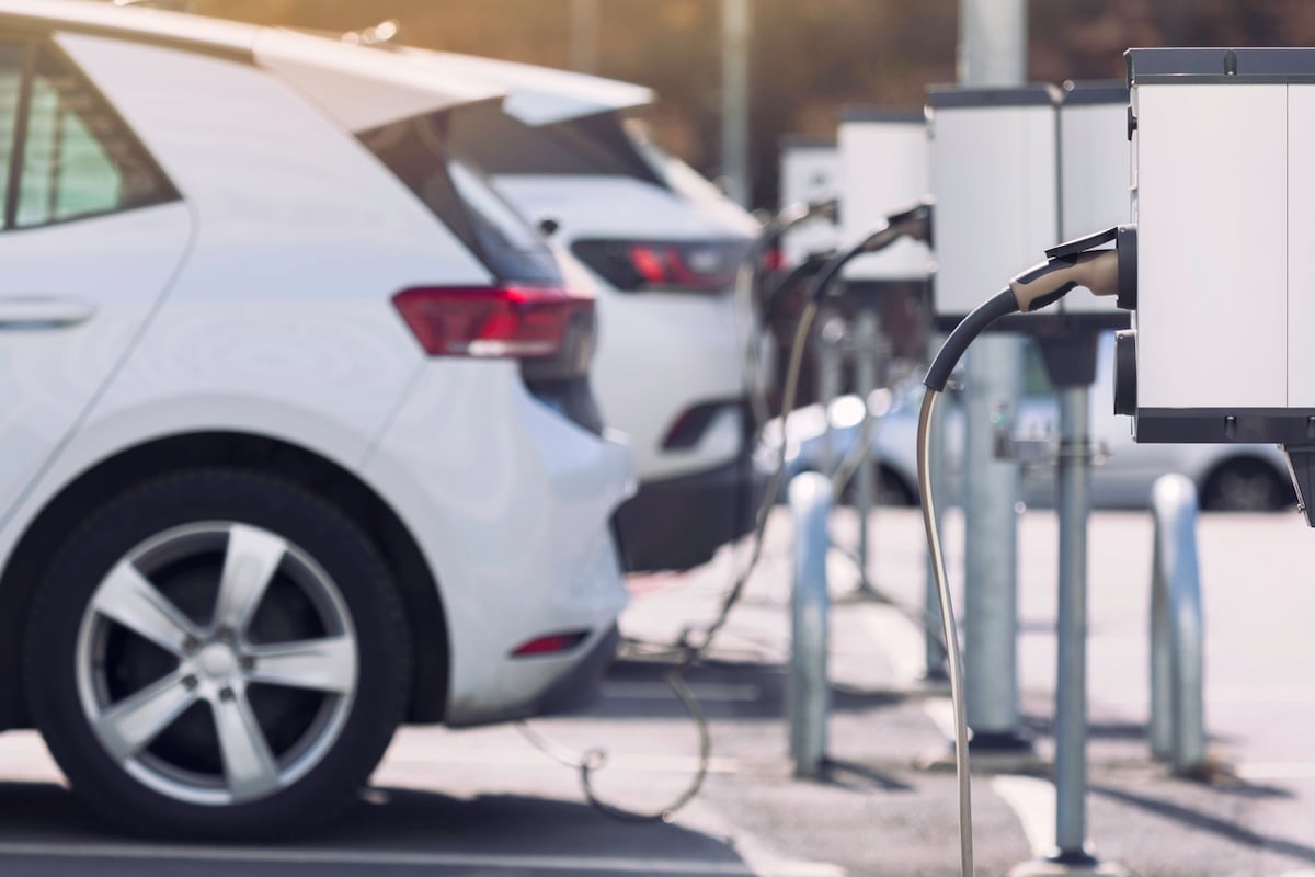 A line of white electric vehicles charging at a charging station