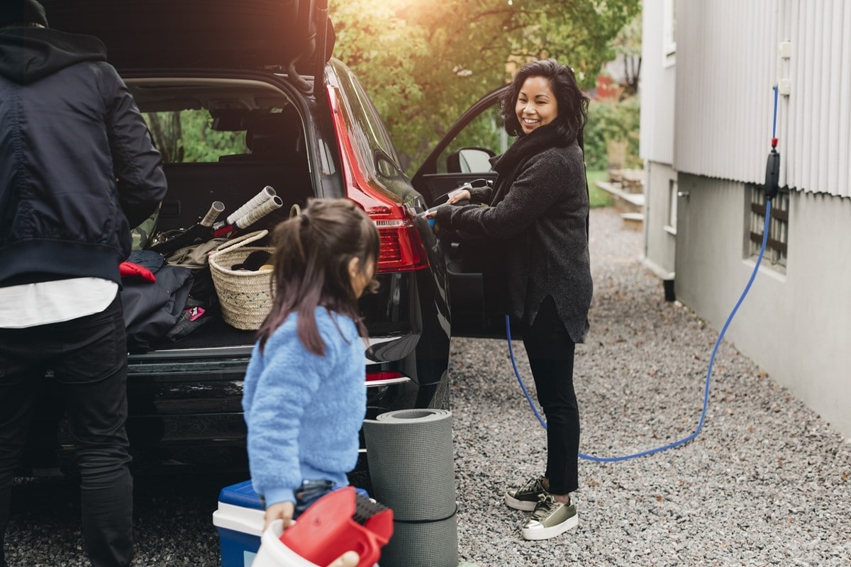 Family unpacking the family electric car while its charging