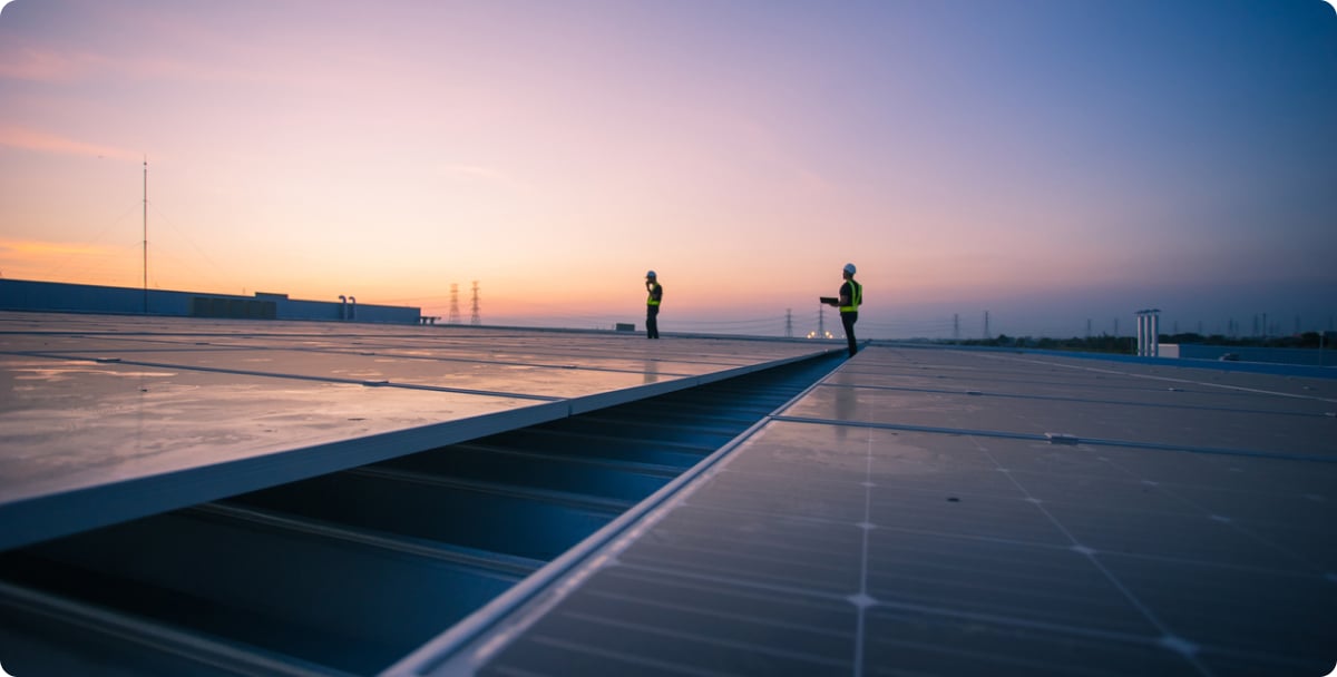 Solar panels on roof at sunrise with workers in the background