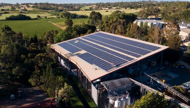 Birds-eye view of a building surrounded by trees with solar panels covering the roof