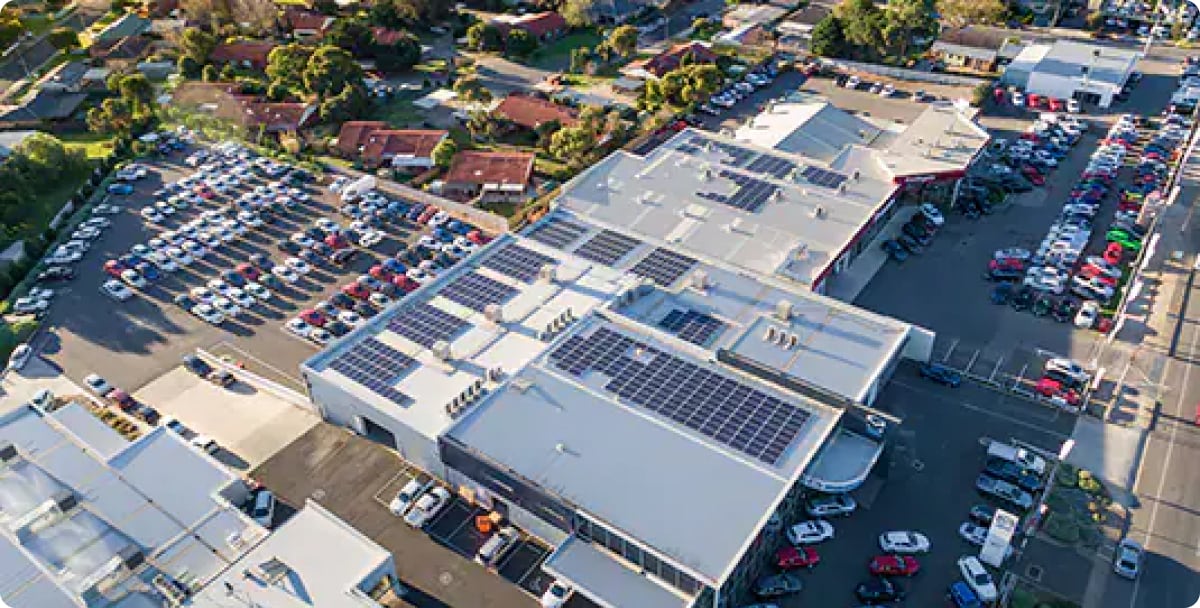 Shot of a building with solar panels on roof with a full carpark