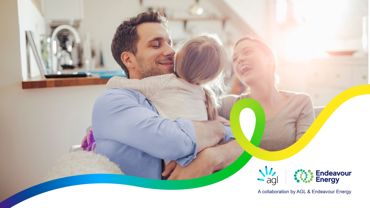 Three people indoors holding a child, with sunlight in the background; a green and yellow graphic overlays the image alongside the text “agl – A collaboration by AGL & Endeavour Energy” and the Endeavour Energy logo.