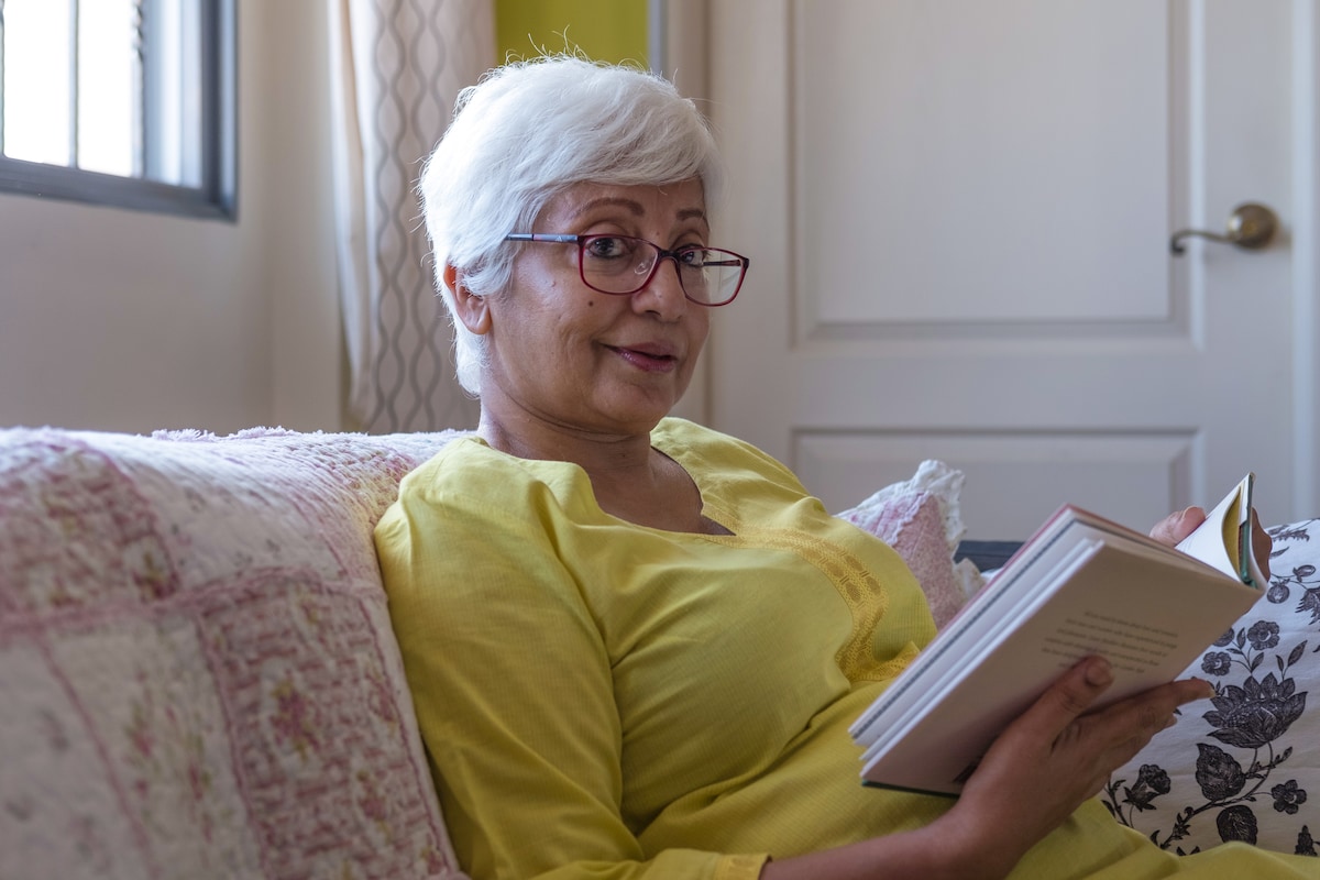 Older lady reading book on couch