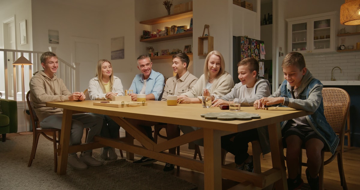 Family at dining table with girl in headphones and tablet 