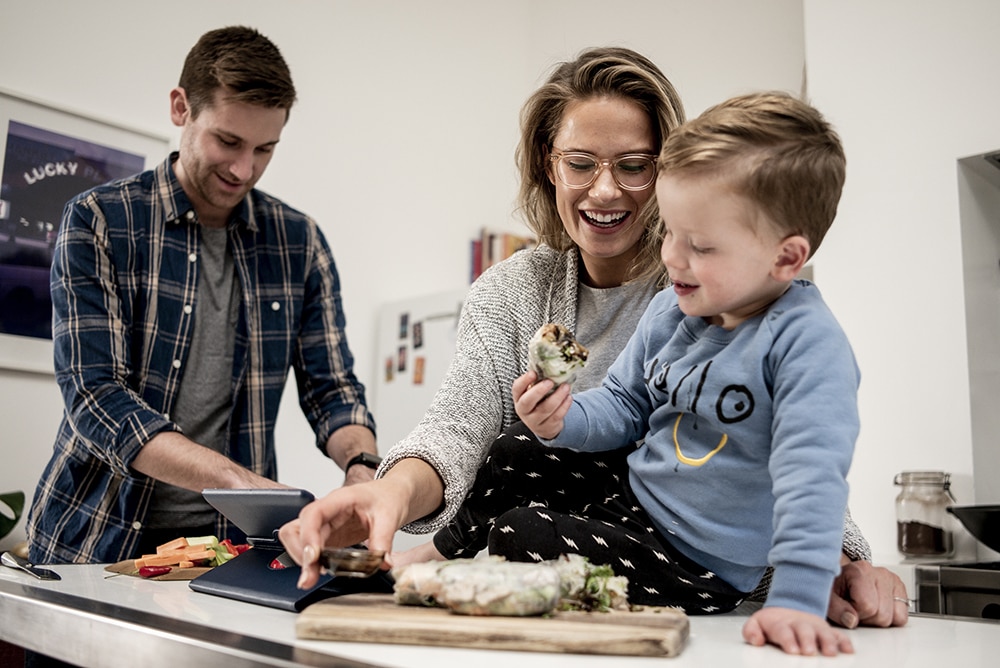 Family cooking in kitchen viewing a recipe on tablet device