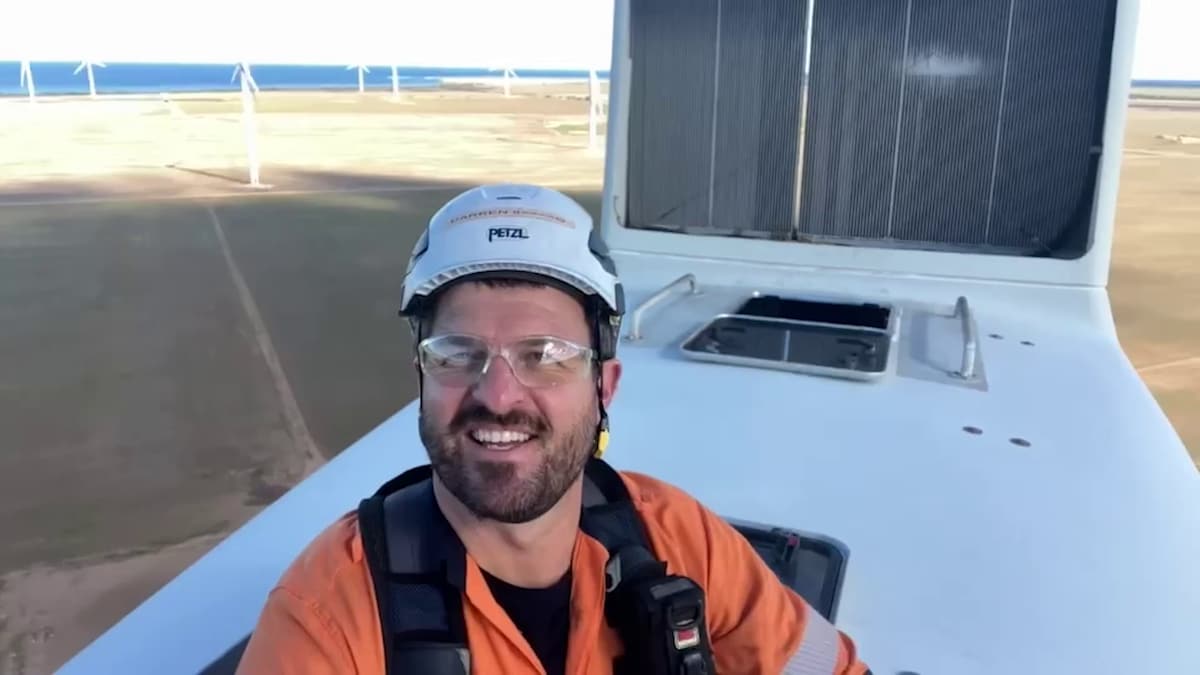 Photo of Darren in a helmet, goggles and high-vis jacket on top of a windmill. 