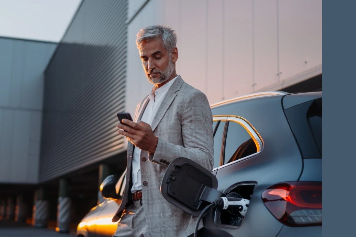 A man stands next to an electric vehicle while it charges