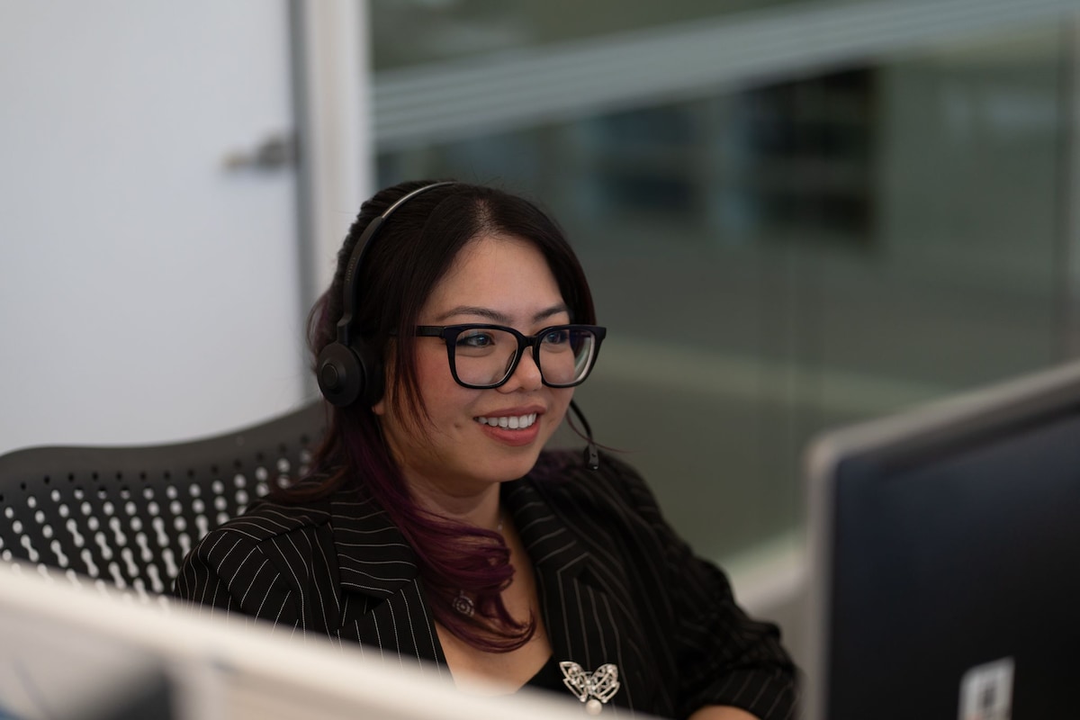 A Customer Solutions employee smiliing with their headset on. 