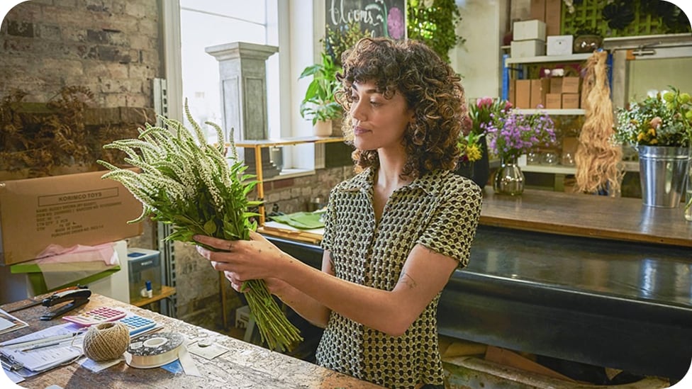 Woman in a checkered shirt, working in a florist shop.