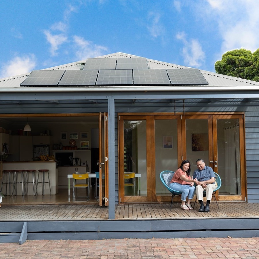 Image of couple sitting outside their home with solar panels on roof