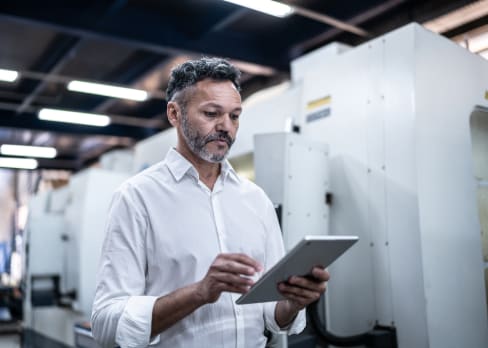 Man standing in an office holding a tablet