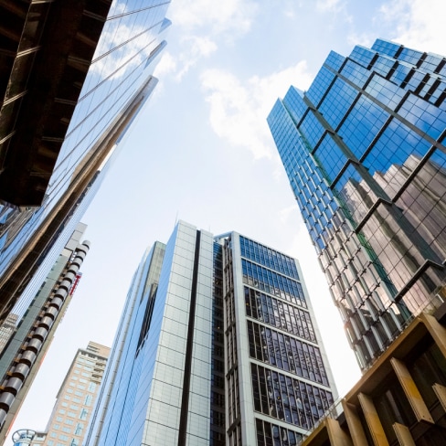 View from the ground of a group of glass-fronted high rise buildings in a city