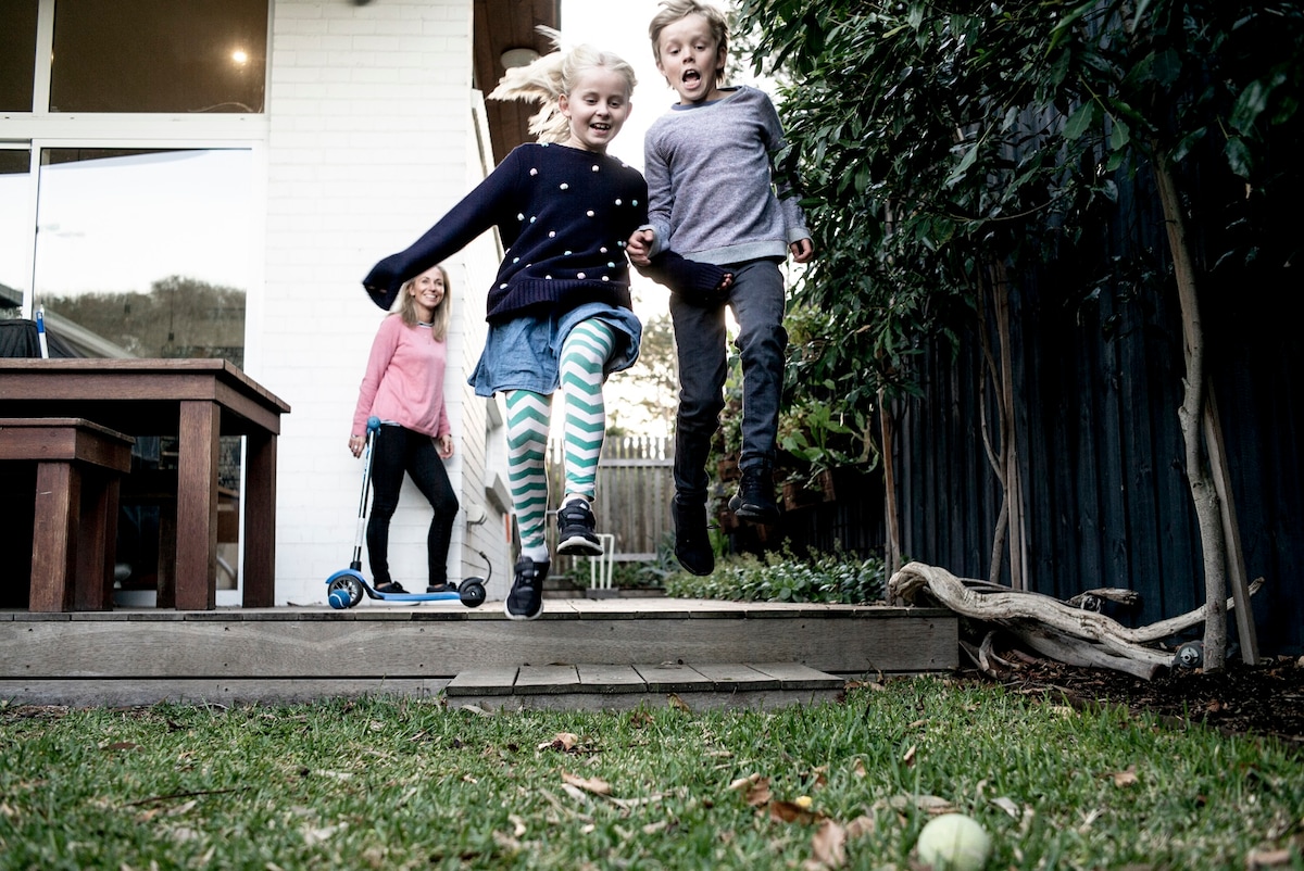 Woman and children outside, children jumping in the air