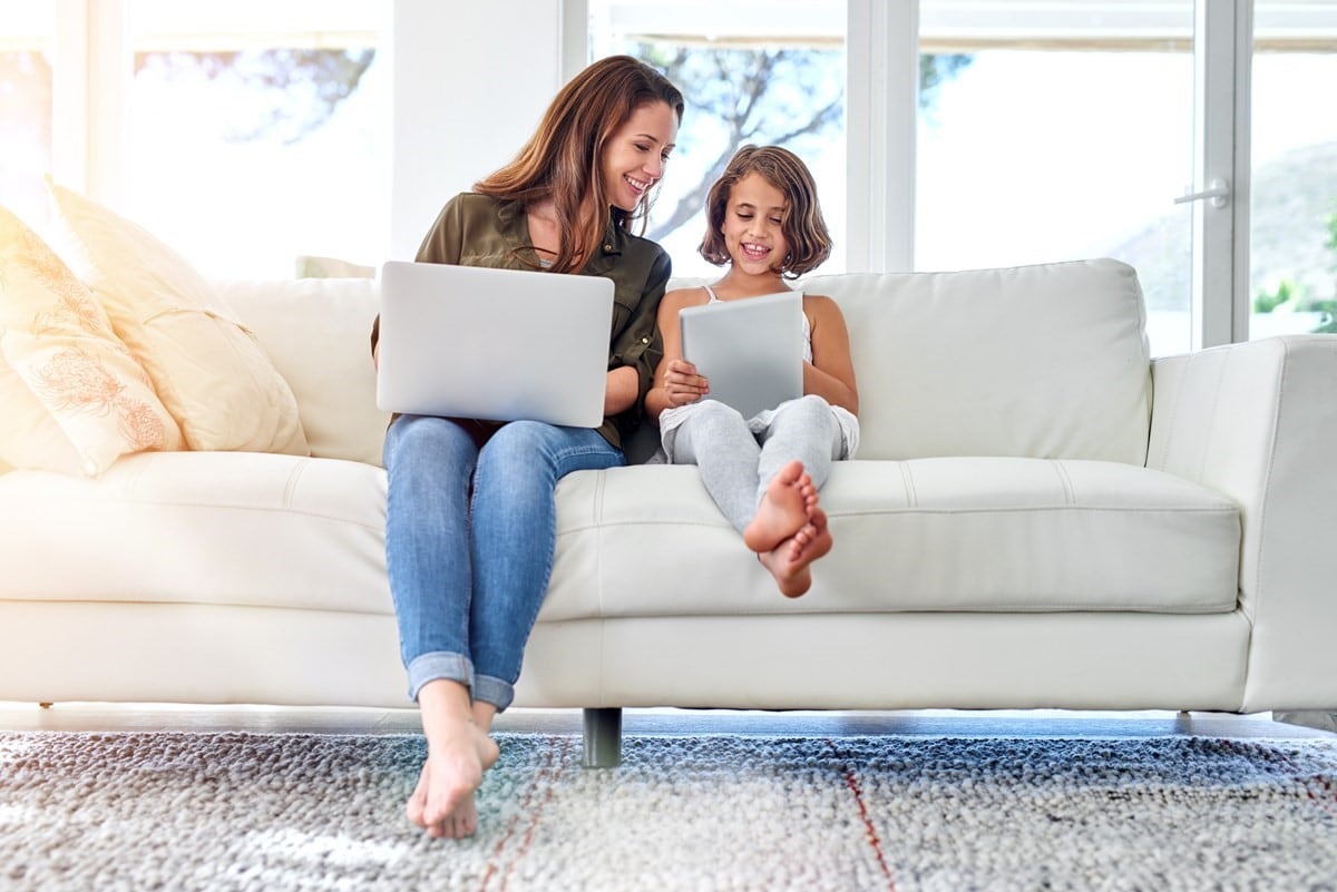 A woman and her child in a lounge room. They are looking at a tablet.