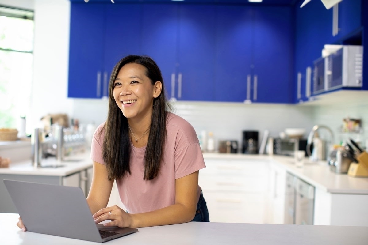 Woman in kitchen using her laptop