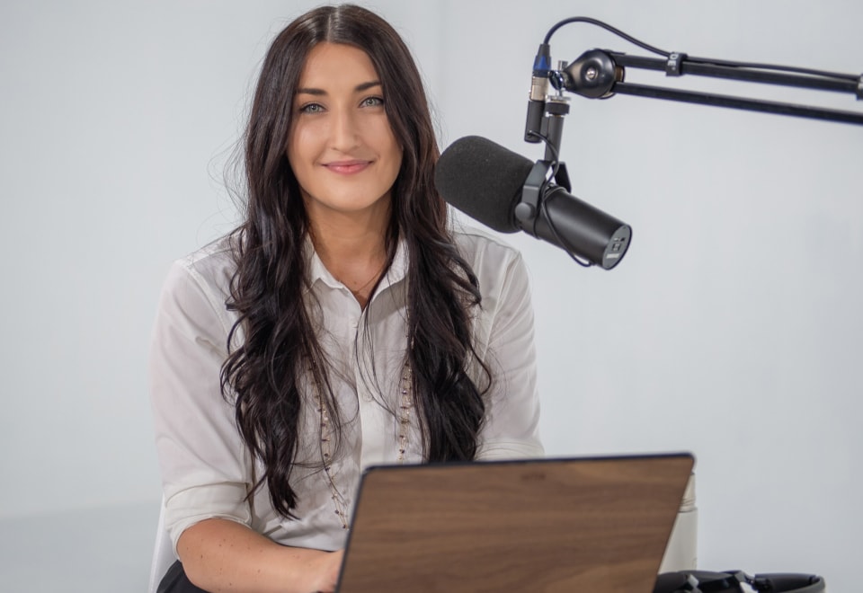 Net Zero for Business Podcast host, Taylor Hawkins, sitting at a desk with a laptop and microphone.