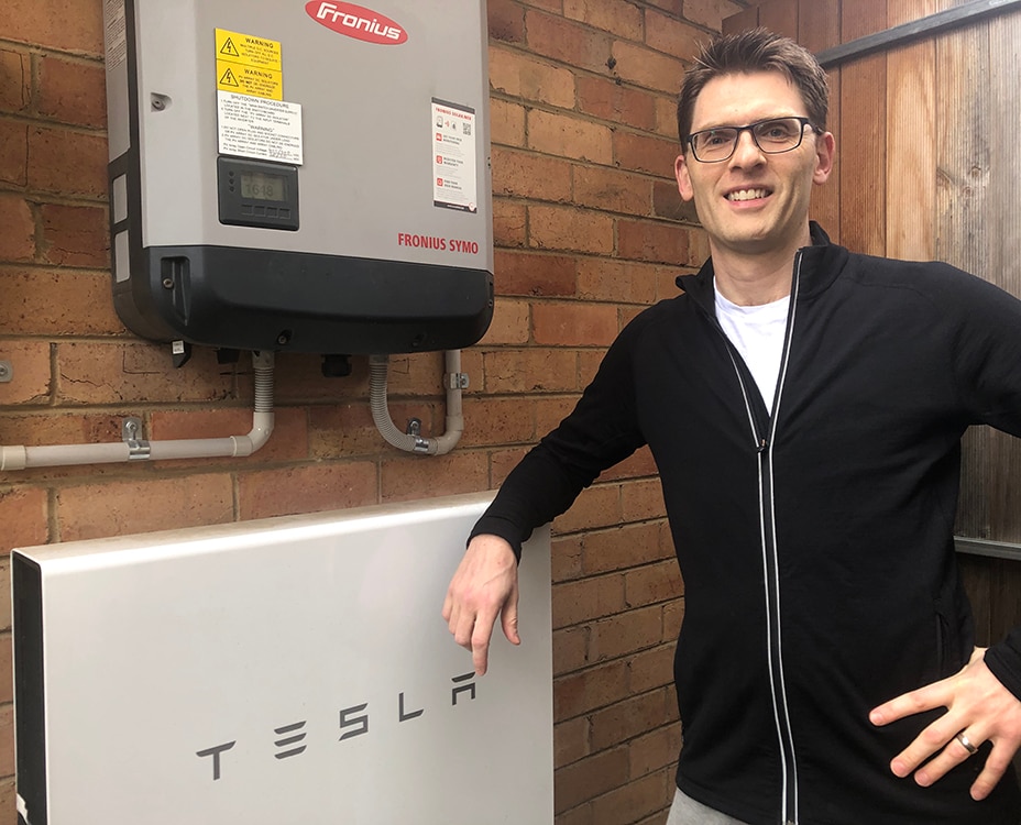 AGL VPP customer Dylan standing next to his Tesla home battery