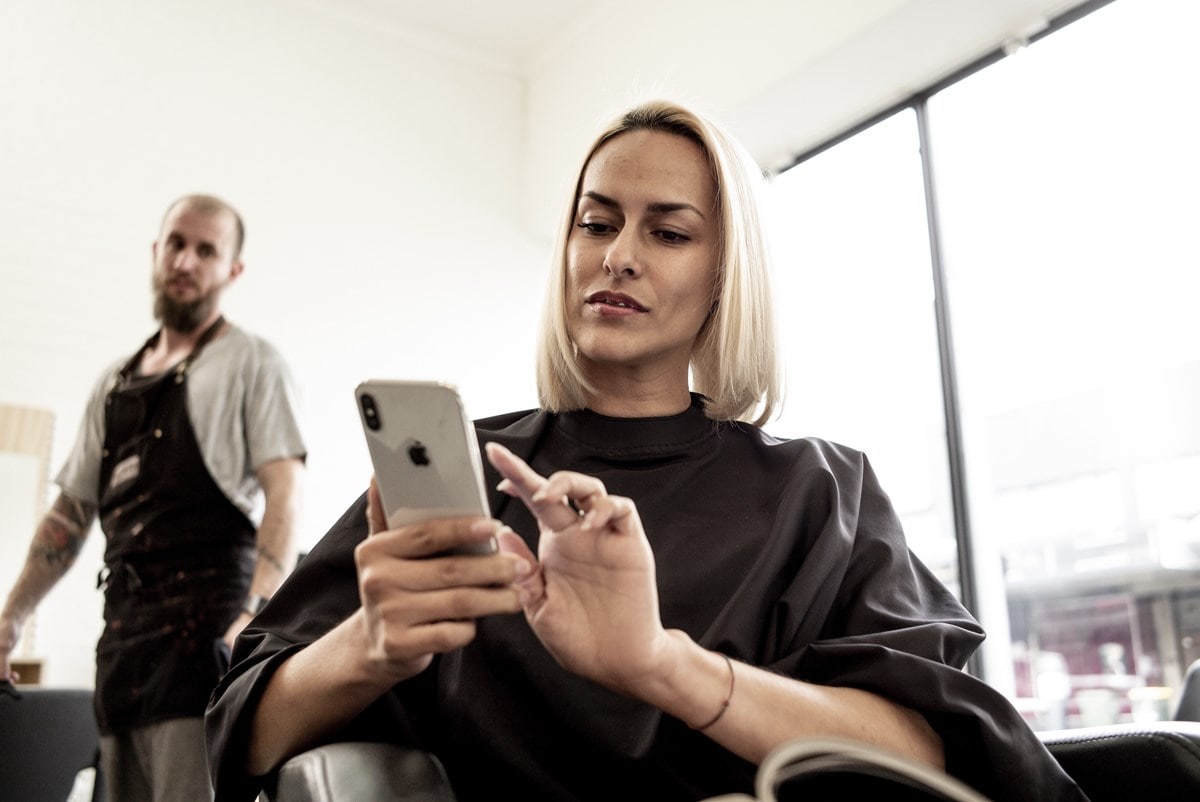 Woman using mobile phone at hairdresser