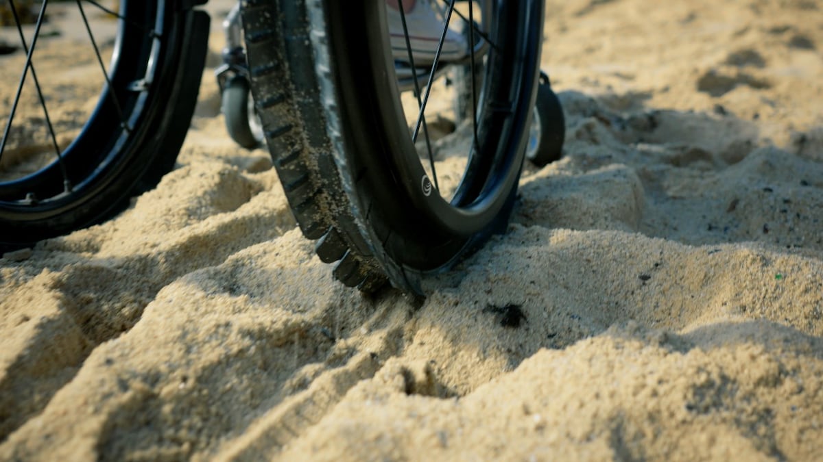 Closeup of a wheelchair being ridden on sand
