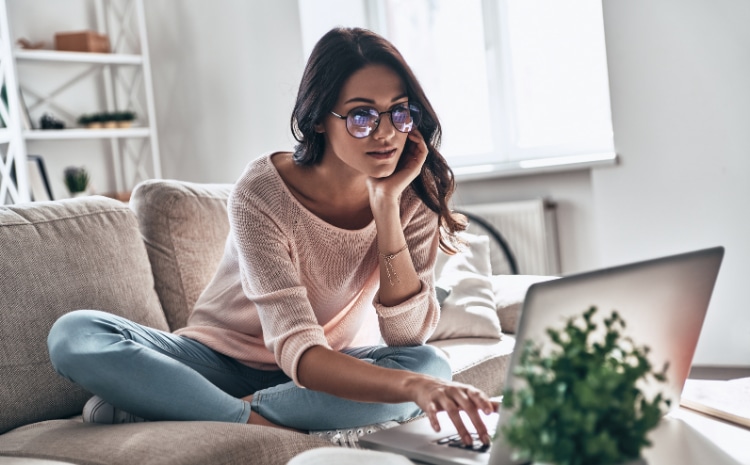 Young woman in glasses on her laptop on her couch