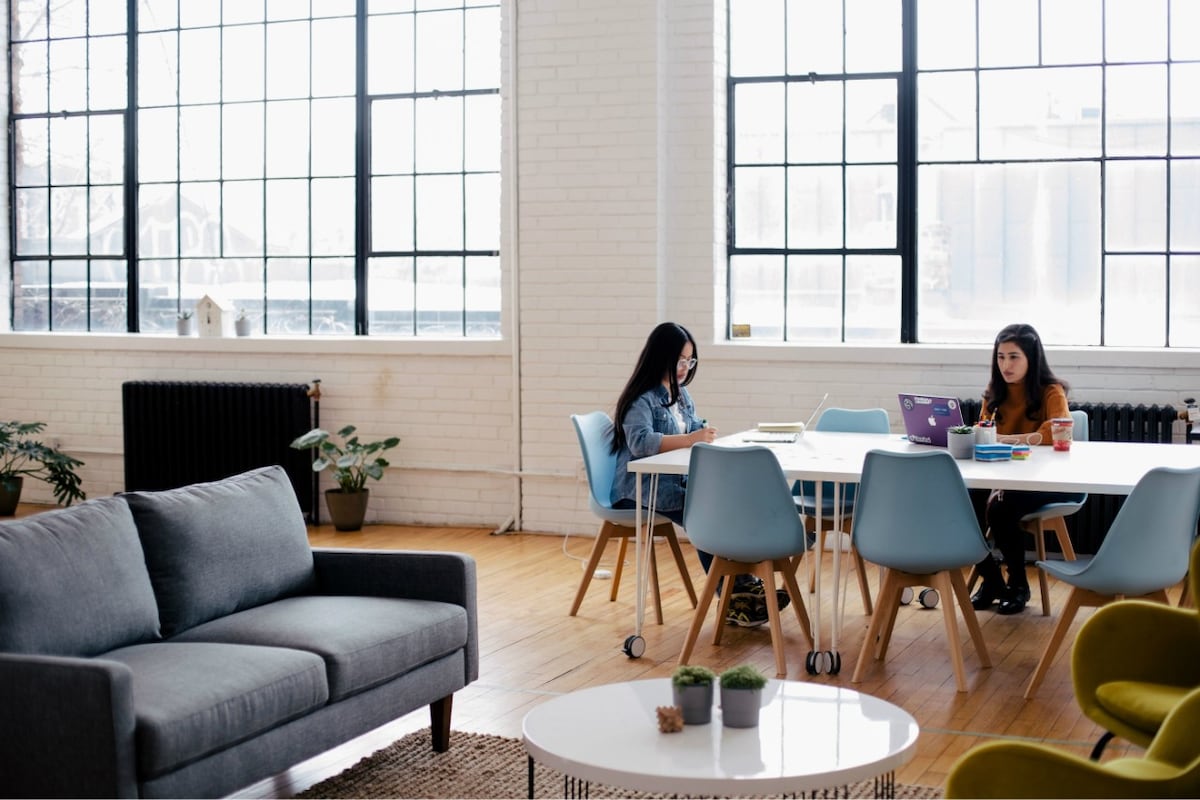 Two women working at a table in an open plan office