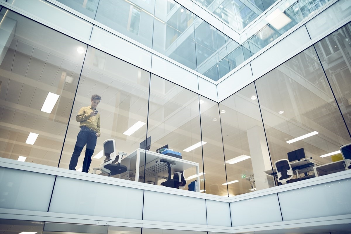 Man standing on phone in front of office windows