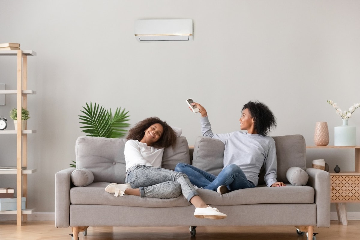 Two women on their couch turning their air con on
