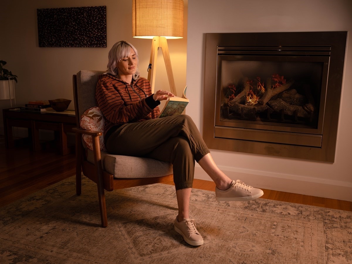 Young woman on lounge in front of gas fireplace