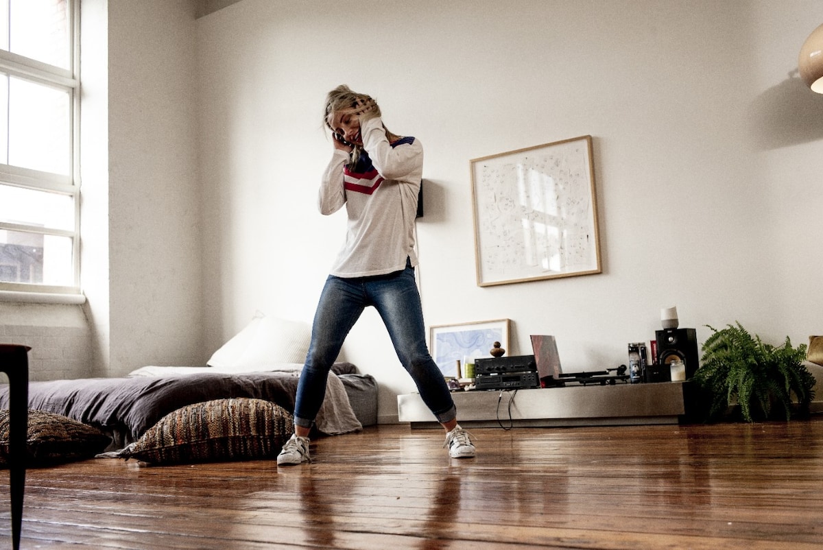 Woman wearing headphones and dancing in lounge room