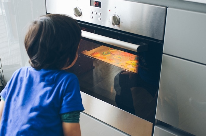 Little boy looking at cookies baking in oven