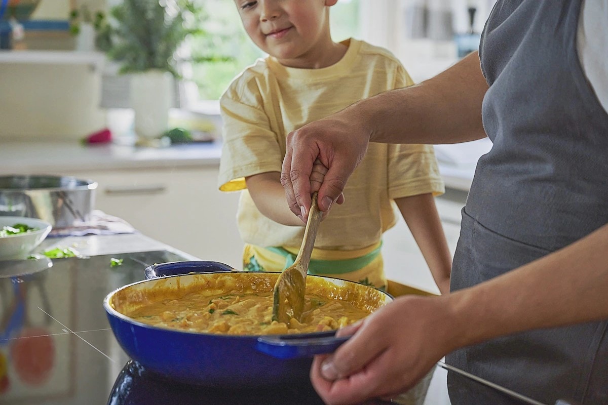 Father and toddler stirring food in a pot