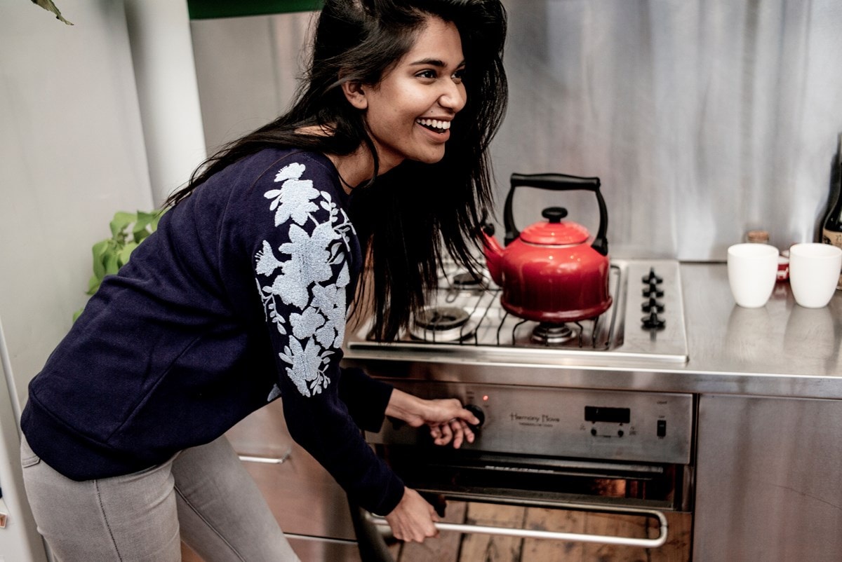 A woman turning on her gas cooktop to boil water in a kettle