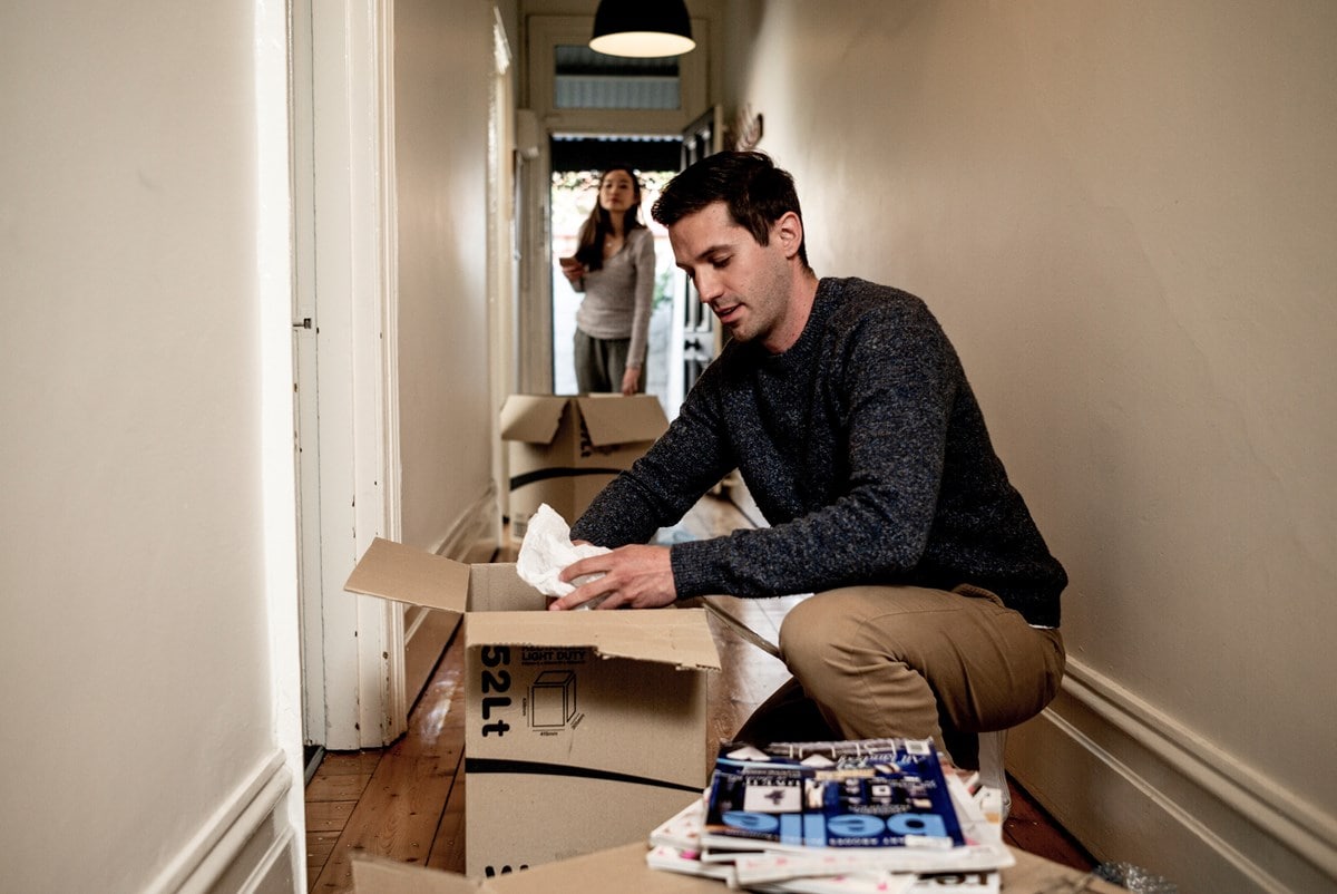 A man and a woman unpacking boxes in the hallway of their house