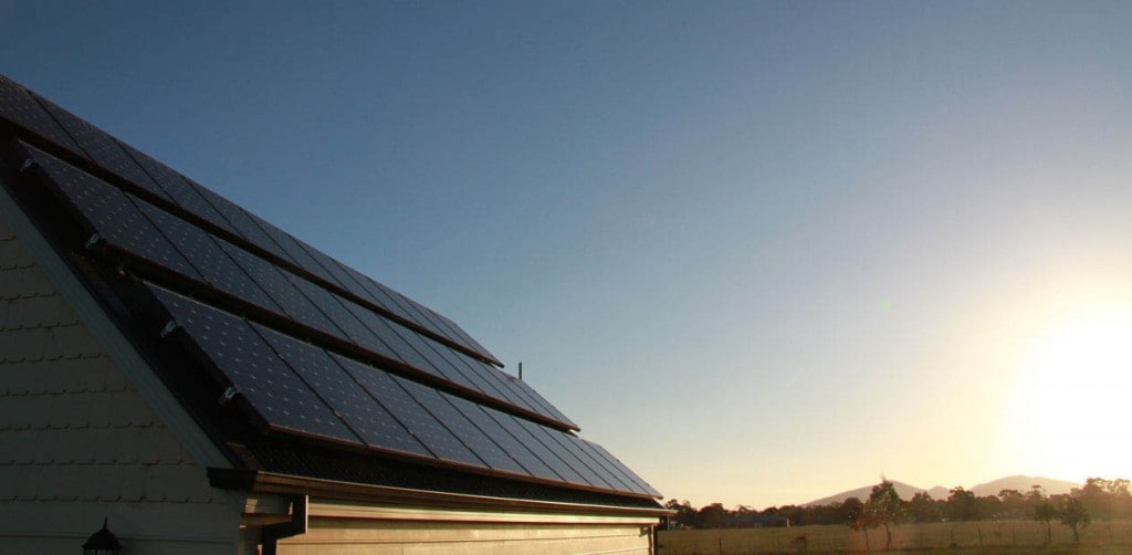 A sunrise going over a house with solar panels