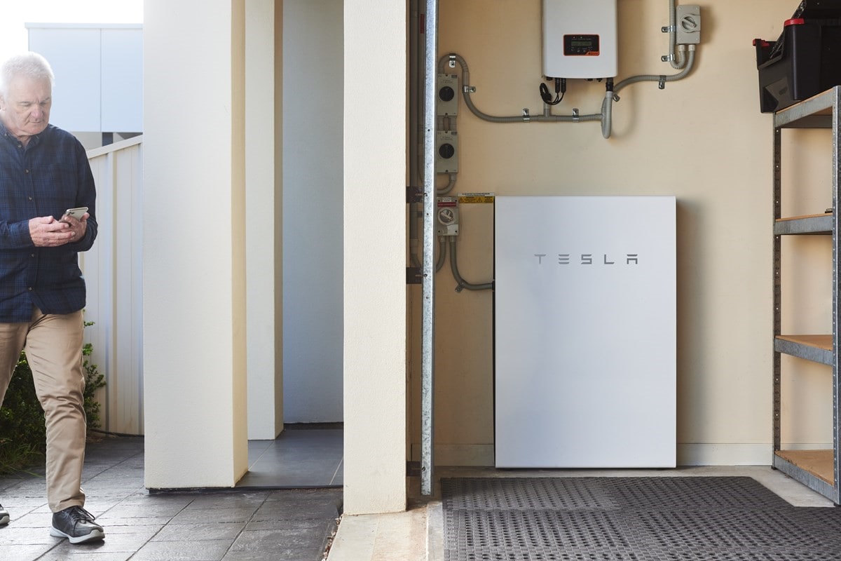 AGL customer Geoff walking towards the Tesla Powerwall battery installed in his garage