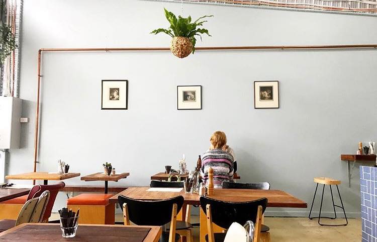 Light-filled cafe with person sitting facing wall