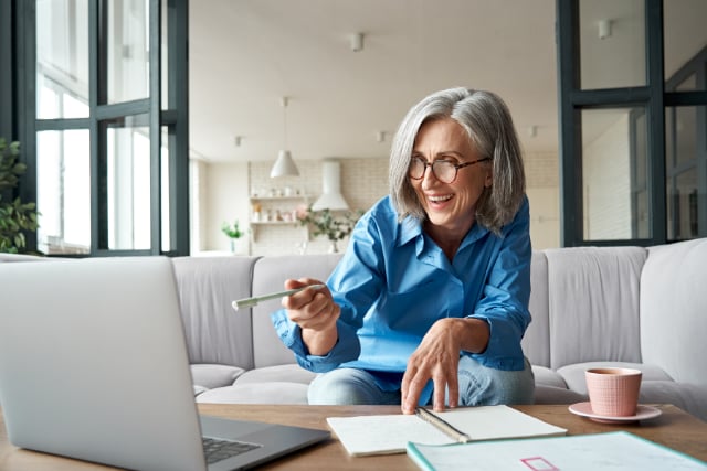 An elderly woman pointing at her laptop