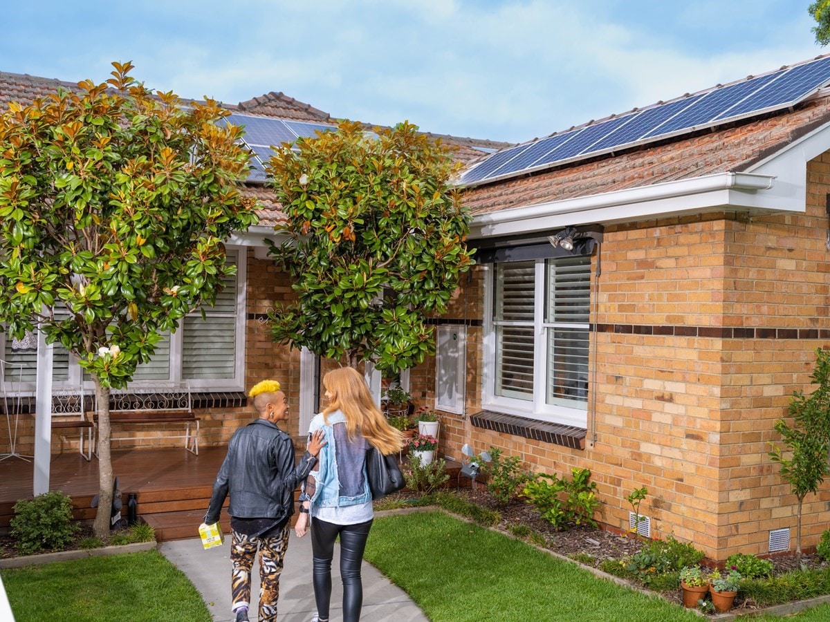 Friends walking towards a house with solar panels on the roof