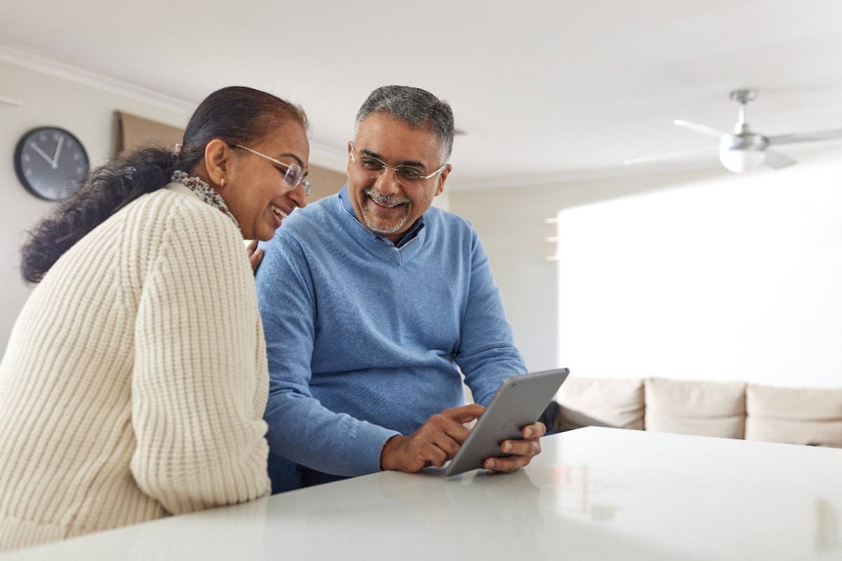Kartik and wife looking at iPad leaning against kitchen bench