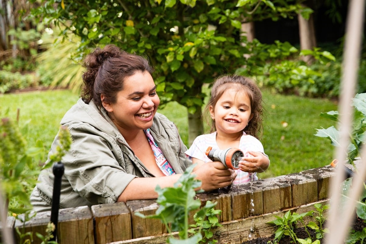 Mother daughter outside watering garden