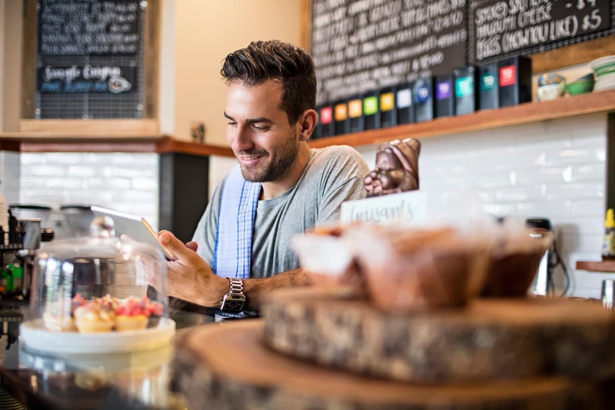 Cafe worker smiling liking at his tablet