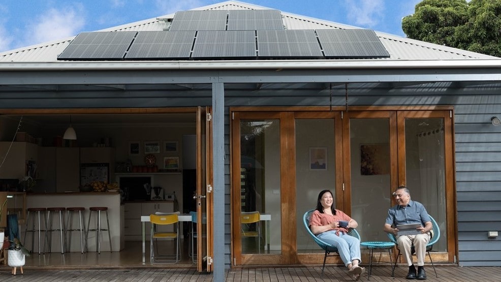 Grandparents sitting on back patio with rooftop solar enjoying sunny day